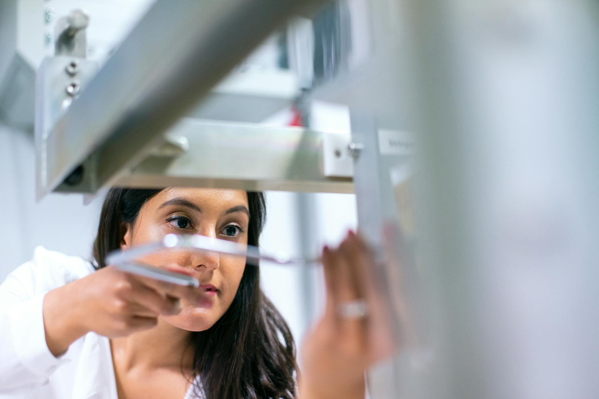 Female engineer focused on equipment in a modern lab, showcasing technology and expertise.
